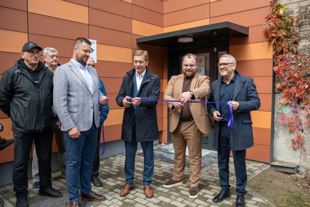 Vyrai prie pastato įėjimo laiko violetinę juostelę atidarymo ceremonijoje