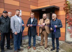 Vyrai prie pastato įėjimo laiko violetinę juostelę atidarymo ceremonijoje