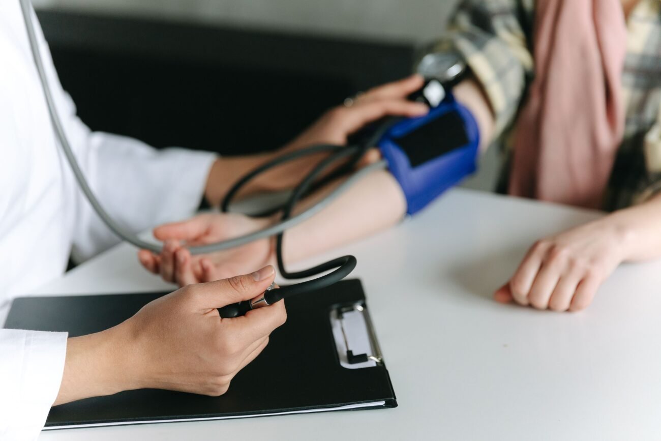 Medikas matuoja paciento kraujospūdį stetoskopu ir manžete