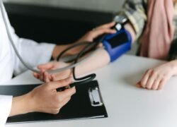 Medikas matuoja paciento kraujospūdį stetoskopu ir manžete