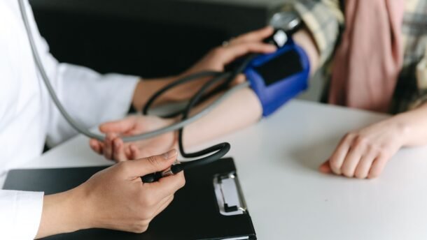 Medikas matuoja paciento kraujospūdį stetoskopu ir manžete