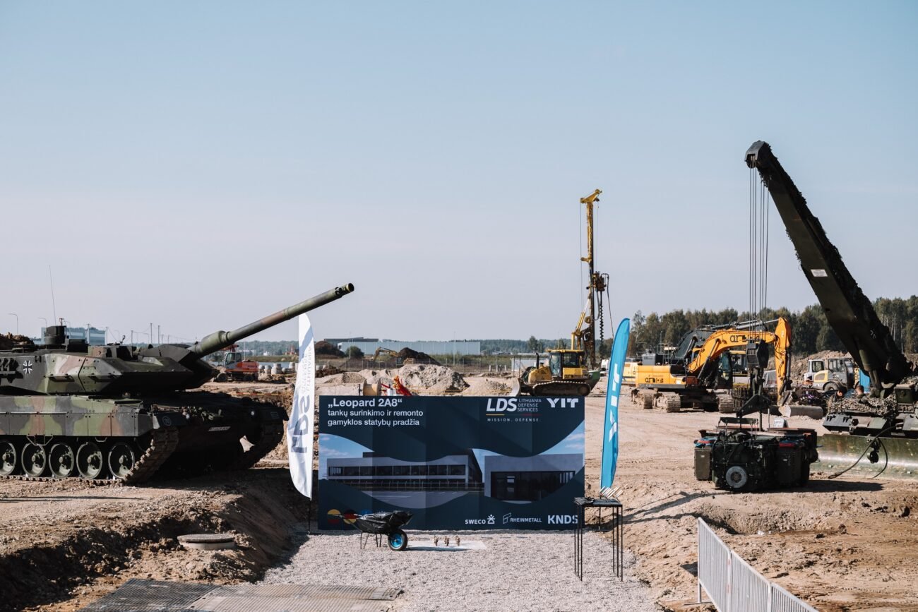 Tankas statybvietėje šalia ekskavatorių, krano ir informacinio stendo