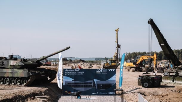 Tankas statybvietėje šalia ekskavatorių, krano ir informacinio stendo