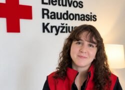 Moteris su Lietuvos Raudonojo Kryžiaus liemene prie organizacijos logotipo