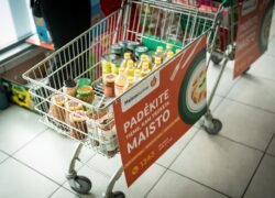 Prekių vežimėlis su maisto produktais ir „Maisto banko“ akcijos plakatu