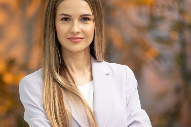 Ilgaplaukė moteris šviesiu švarku rudeniškame fone