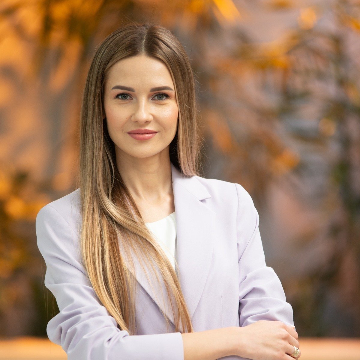 Ilgaplaukė moteris šviesiu švarku rudeniškame fone