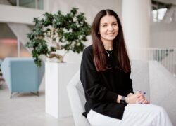 Besijuokianti moteris sėdi šviesiame biuro interjere