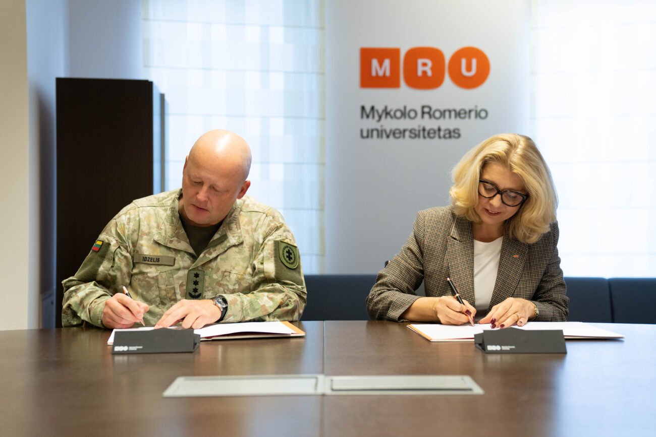 Du žmonės pasirašo dokumentus prie stalo Mykolo Romerio universitete