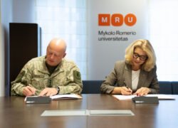 Du žmonės pasirašo dokumentus prie stalo Mykolo Romerio universitete