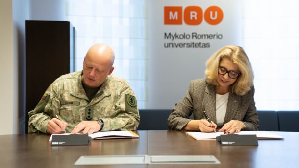 Du žmonės pasirašo dokumentus prie stalo Mykolo Romerio universitete