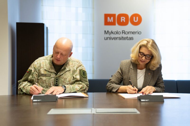 Du žmonės pasirašo dokumentus prie stalo Mykolo Romerio universitete