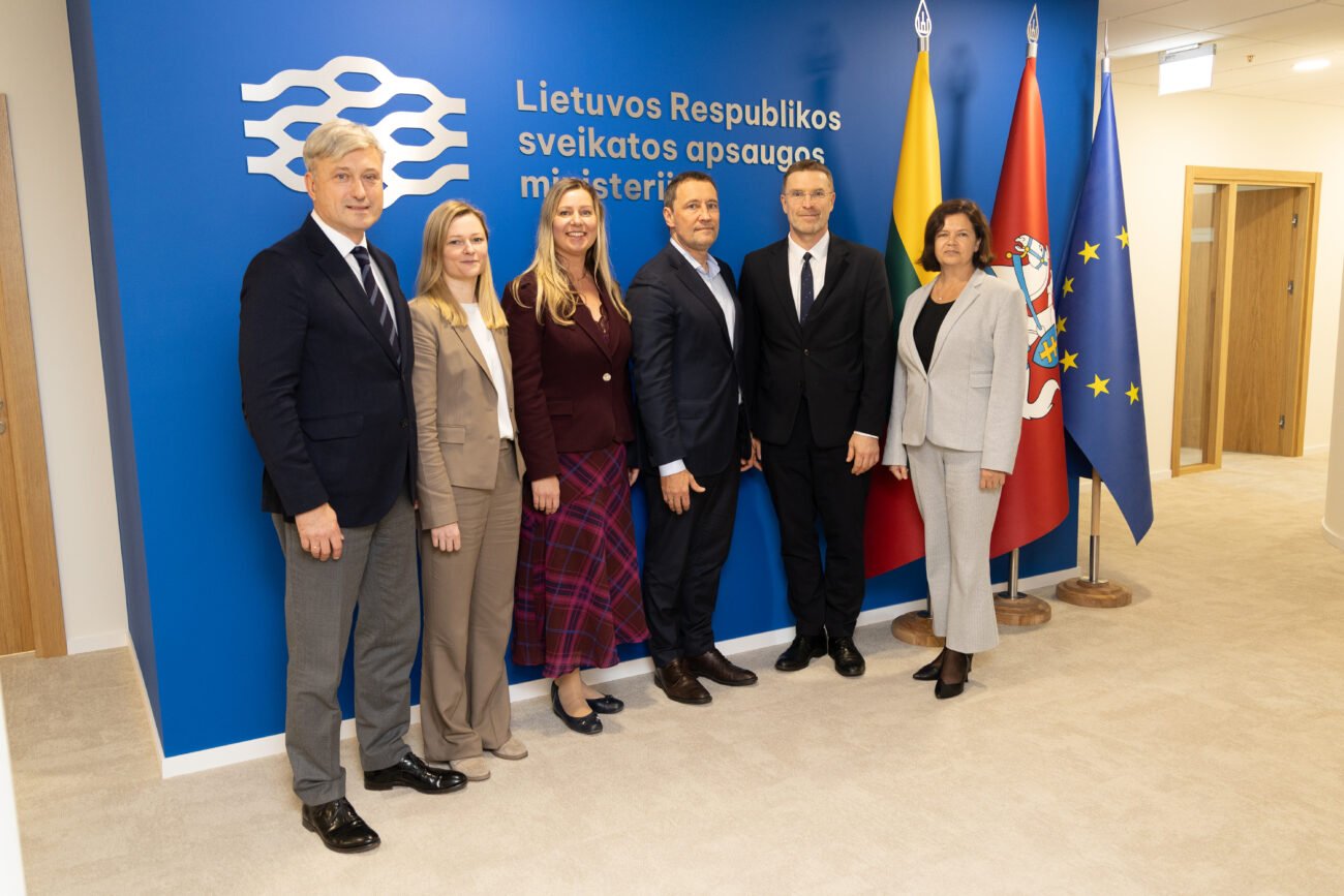 Šeši žmonės pozuoja prie Lietuvos Respublikos sveikatos apsaugos ministerijos sienelės