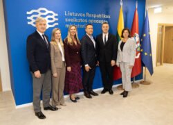 Šeši žmonės pozuoja prie Lietuvos Respublikos sveikatos apsaugos ministerijos sienelės