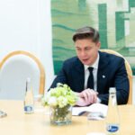 Premjeras sėdi prie stalo šalia Lietuvos ir Europos Sąjungos vėliavų