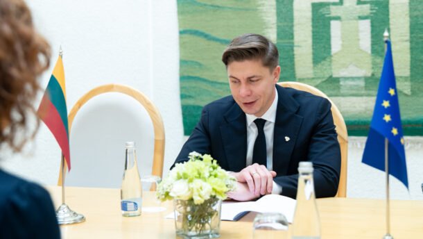 Premjeras sėdi prie stalo šalia Lietuvos ir Europos Sąjungos vėliavų