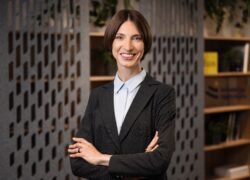 Besimanys moteris stovi sukryžiavusi rankas moderniame biure