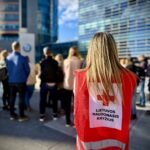 Lietuvos Raudonojo Kryžiaus savanorė raudona liemene stovi žmonių minioje