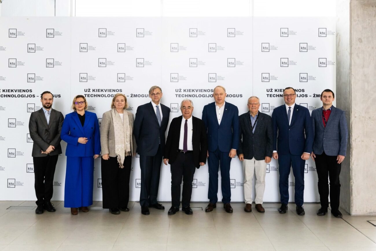Dešimt renginio dalyvių pozuoja prie konferencijos sienelės