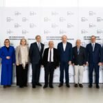 Dešimt renginio dalyvių pozuoja prie konferencijos sienelės