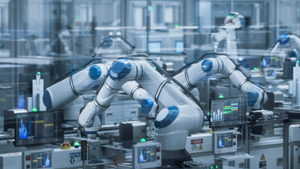 Pramoninėje gamykloje dirbančios robotinės rankos prie gamybos įrangos
