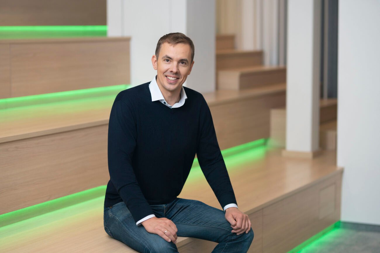 Rokas Šalaševičius sėdi ant medinių laiptų su žaliu apšvietimu