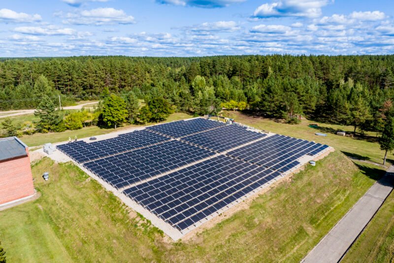 Ant žolės įrengta didelė saulės elektrinė šalia miško