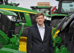 Sergej Artemiuk stovi tarp žalių žemės ūkio traktorių