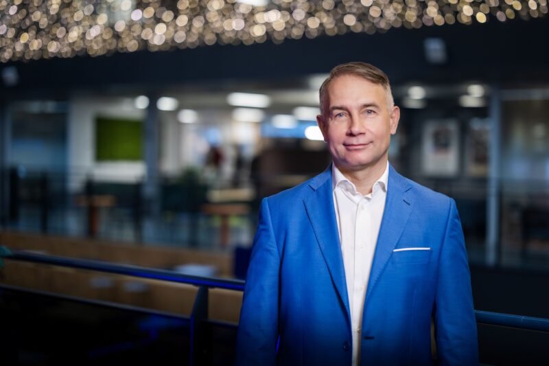 Verslo atstovas mėlynu kostiumu stovi modernioje patalpoje