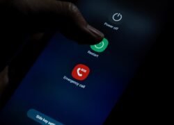 Išmaniojo telefono ekrane atvertas perkrovimo meniu, pirštas liečia mygtuką „Restart“