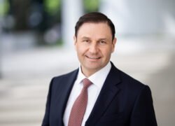 Besijuokiantis verslininkas su tamsiu kostiumu ir raudonu kaklaraiščiu