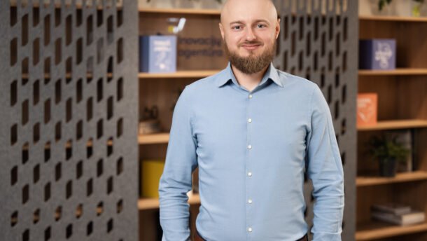 Besidriekiantis vyras šviesiais marškiniais moderniame biuro interjere