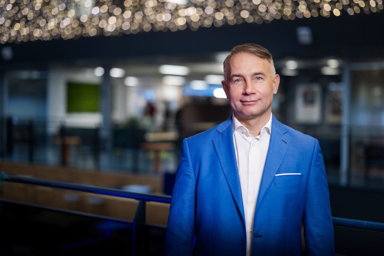 Mėlynu kostiumu vilkintis vyras stovi modernioje verslo aplinkoje