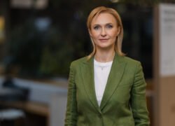 Verslo moteris žalia striuke stovi biuro aplinkoje