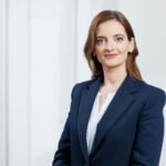 Verslo moters portretas su tamsiai mėlynu švarku šviesiame biure