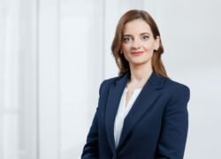 Verslo moters portretas su tamsiai mėlynu švarku šviesiame biure