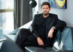Vyras juodu kostiumu sėdi ant sofos moderniame interjere
