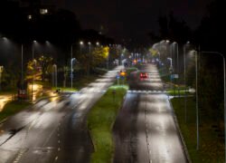 Lietingą naktį apšviesta Vilniaus gatvė su automobilių eismu