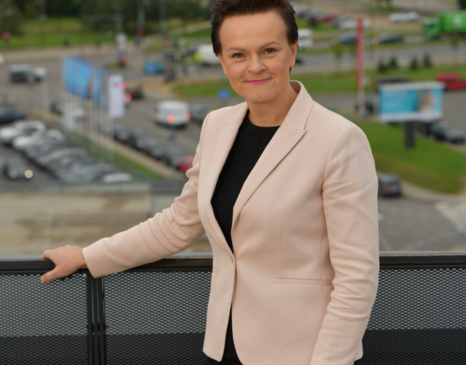 Moteris stovi miesto terasoje, už jos matyti gatvės ir žaliosios teritorijos