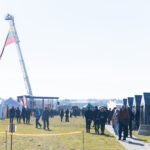 Palapinių miestelis ir žmonės atviroje aikštėje su iškelta vėliava