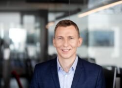 Besišypsantis vyras mėlynu kostiumu moderniame biure