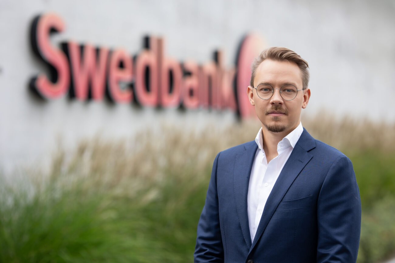 Vyras su mėlynu kostiumu prie „Swedbank“ užrašo