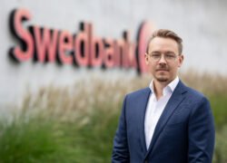 Vyras su mėlynu kostiumu prie „Swedbank“ užrašo