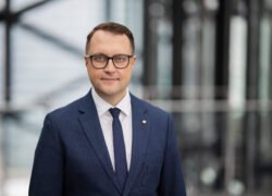 Vyras su akiniais ir kostiumu moderniame biuro interjere
