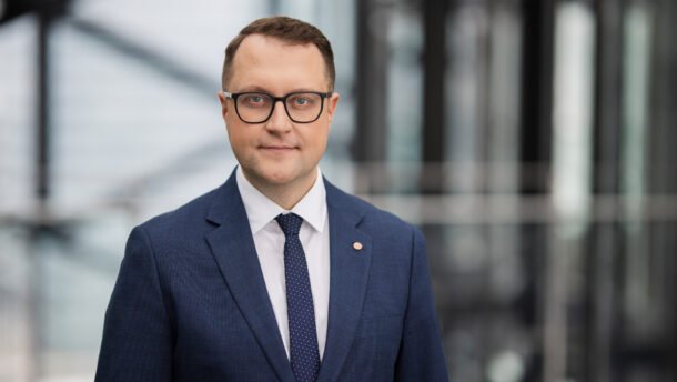 Vyras su akiniais ir kostiumu moderniame biuro interjere