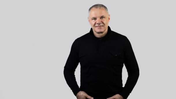 Vyro portretas juodu megztiniu pilkame fone
