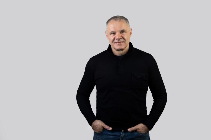 Vyro portretas juodu megztiniu pilkame fone