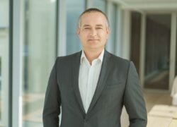 Vyras su pilku kostiumu stovi moderniame pastato interjere