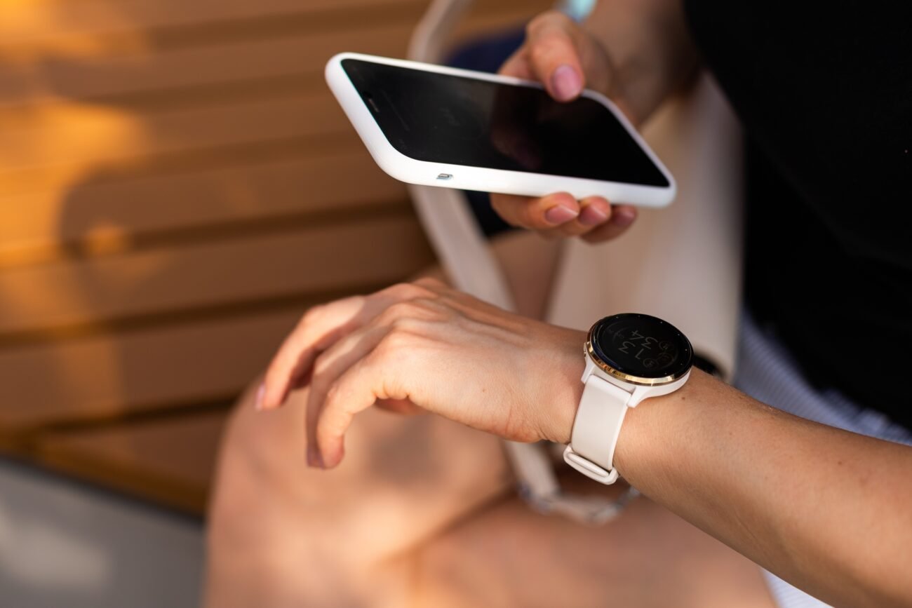 Išmanusis telefonas ir apvalus išmanusis laikrodis ant rankų