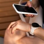 Išmanusis telefonas ir apvalus išmanusis laikrodis ant rankų